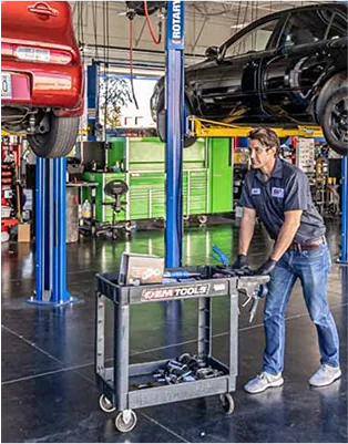Mechanic working on car under lift in garage with tools