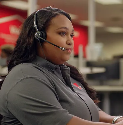 Woman wearing headset in office setting with red Coca-Cola logo on shirt