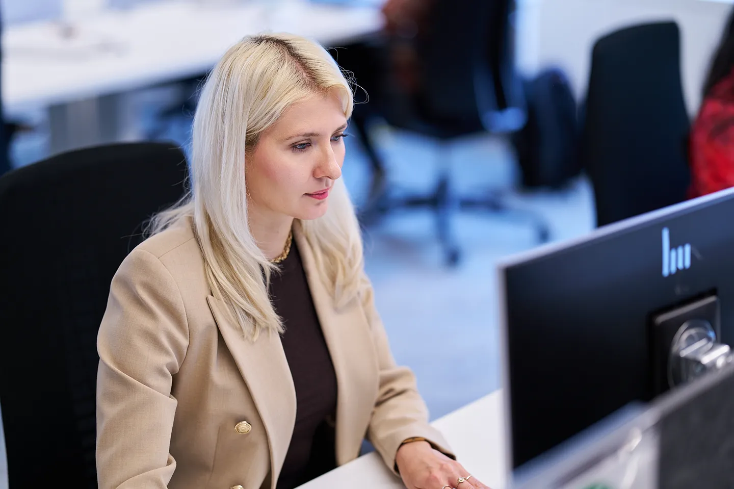 A focused corporate employee is working at her desk in a bright, modern office.