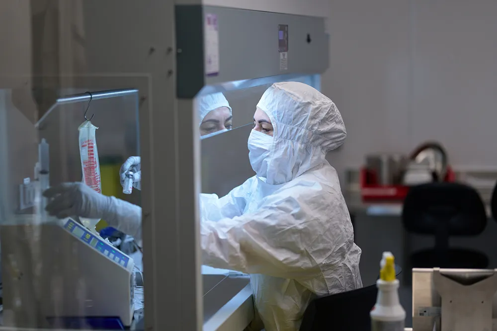 A lab technician in a full clean suit is conducting medical research in a sterile lab environment