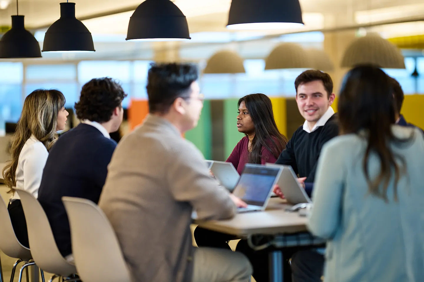 A diverse group of smiling professionals is having a collaborative meeting in a modern office