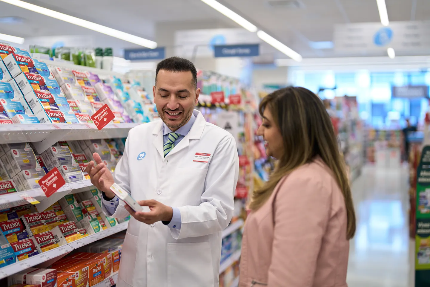 A smiling pharmacist is helping a customer with an over-the-counter medication selection