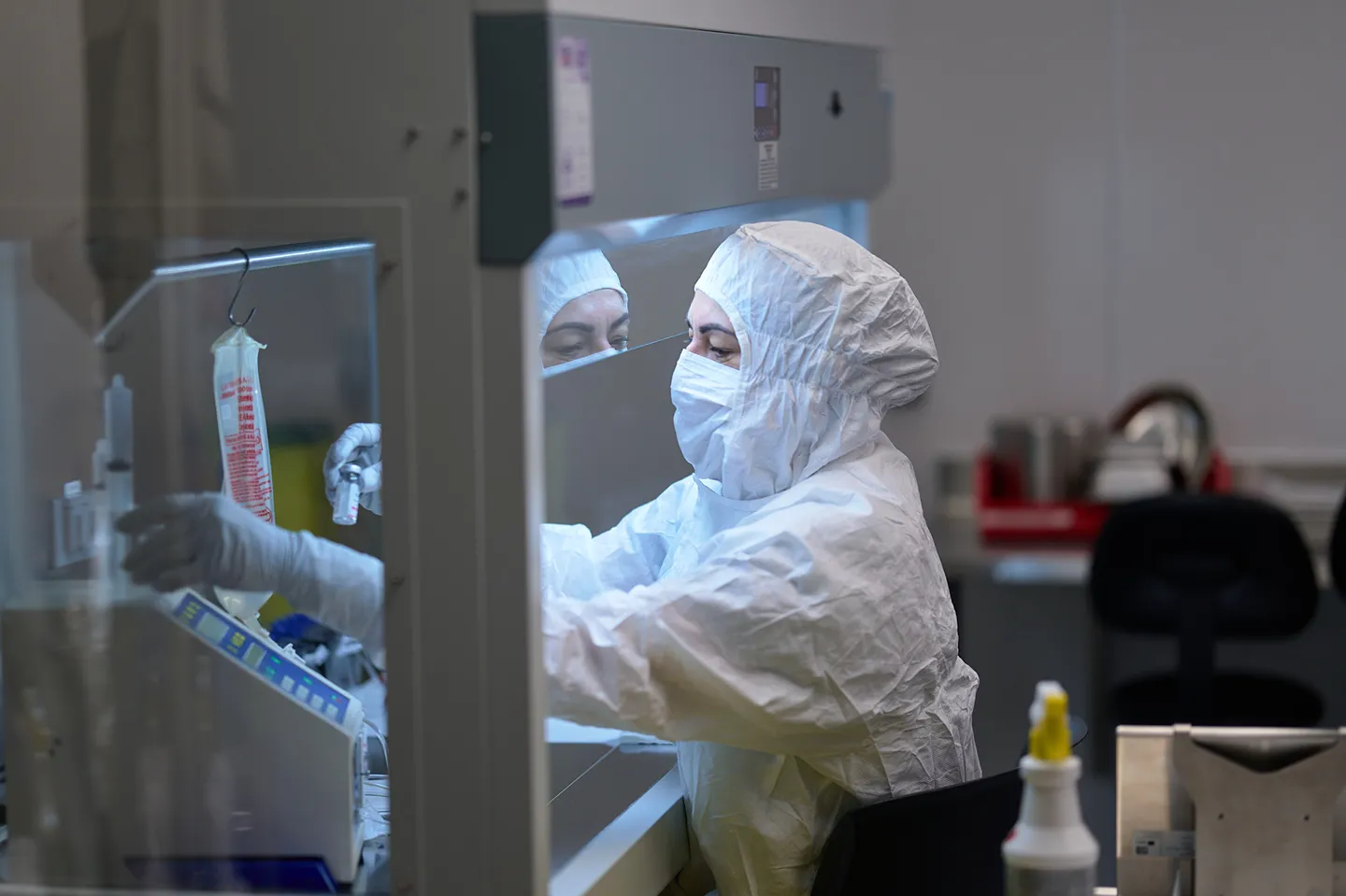 A professional in a clean suit is conducting medical research in a sterile laboratory environment