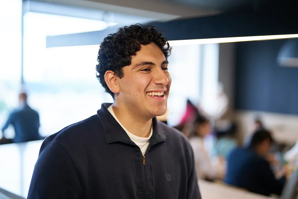 A happy young professional is smiling while collaborating with a colleague in a modern office
