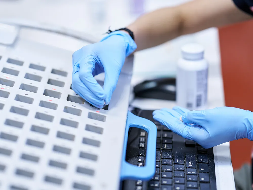 A close-up of a professional in gloves working with a pill packaging machine.