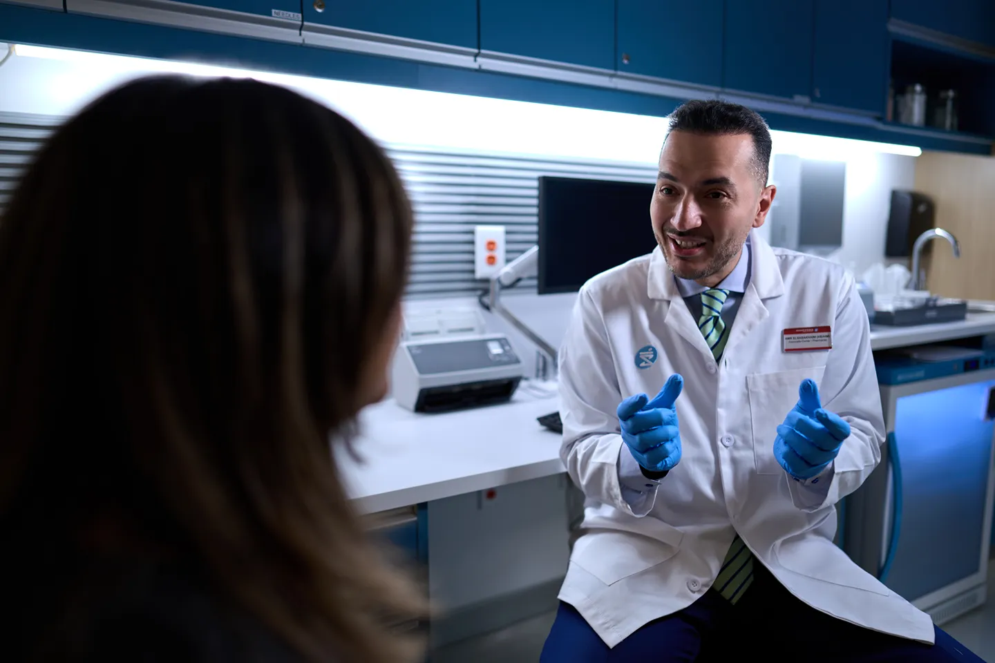 A male pharmacist is smiling and talking to a customer in a medical office