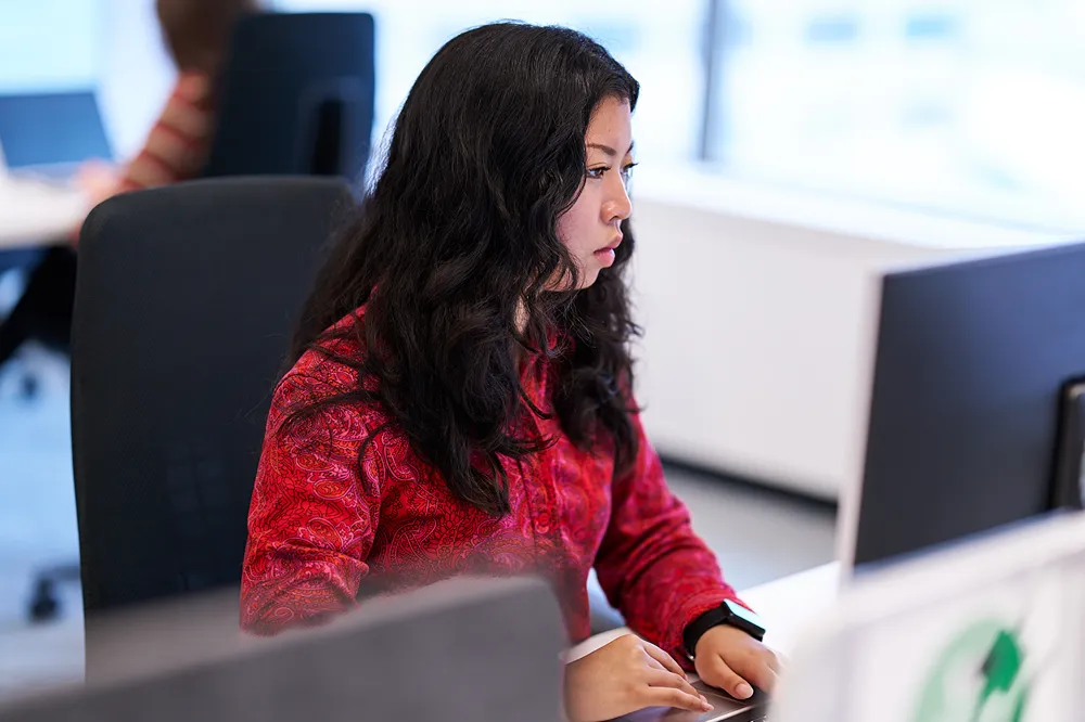 A professional is concentrating while working on her computer in an open-concept office
