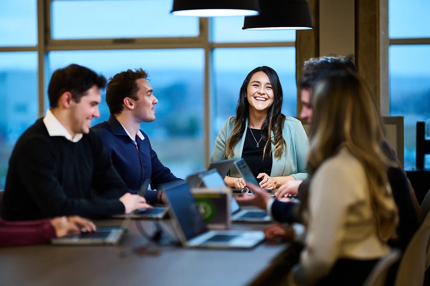 A diverse group of cheerful young professionals is working together at a table