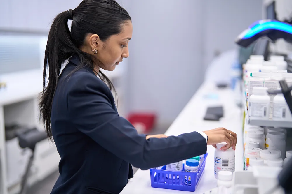 A professional pharmacist is organizing medication bottles on a shelf in a clean pharmacy setting