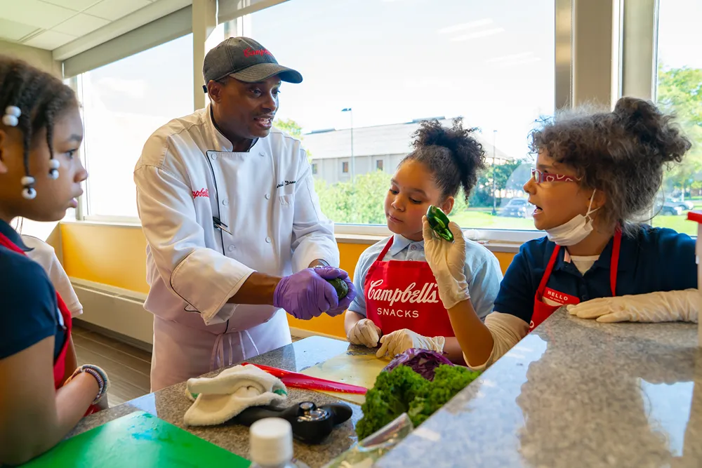 A chef teaches children how to prepare vegetables in a cooking class
