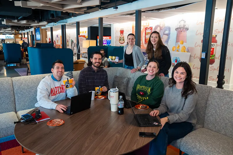 A group of smiling colleagues enjoying a break together in a modern office setting