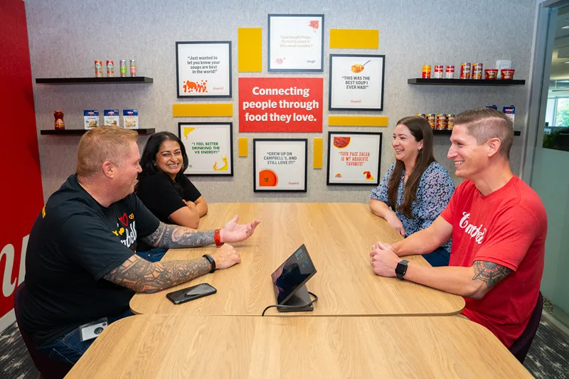 Four colleagues collaborate around a table in a brightly lit office