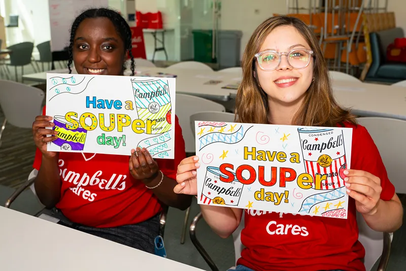 A group of enthusiastic Campbell's employees in red Campbells Cares t-shirts celebrate together