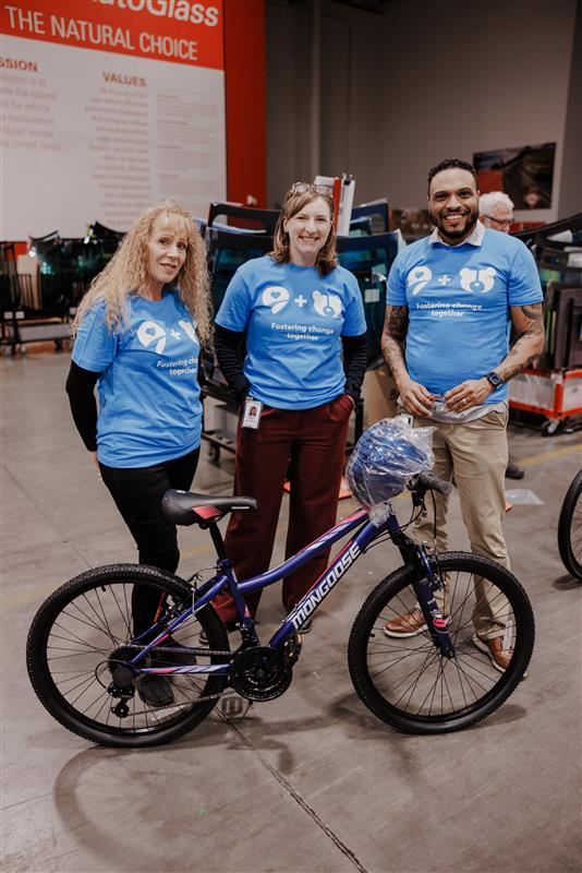 A Safelite technician with a clipboard speaking to a customer next to a white Jeep in a driveway