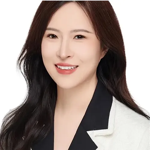 A headshot of a woman in a white jacket and black shirt