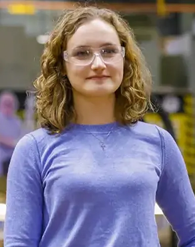 A woman wearing safety goggles standing on a factory floor
