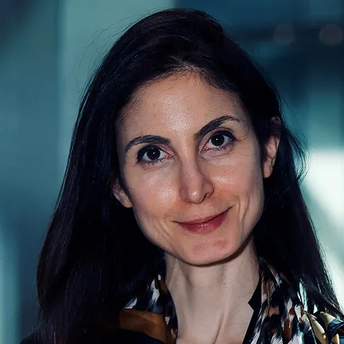 A photo of a woman with dark black hair smiling at the camera