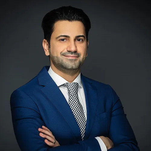 A photo of a man in a blue suit with his arms crossed