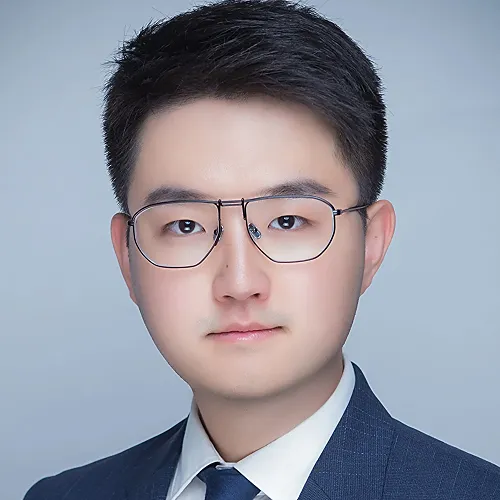 A man wearing glasses and suit looks intently ahead with a white background