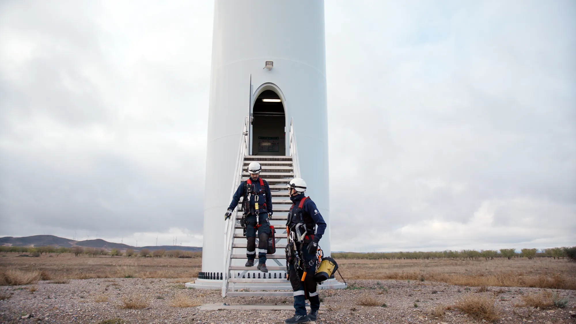 A group of people standing at the staircase entrance to a wind turbine