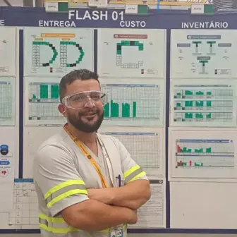 A man wearing safety goggles stands in front of a board containing documents