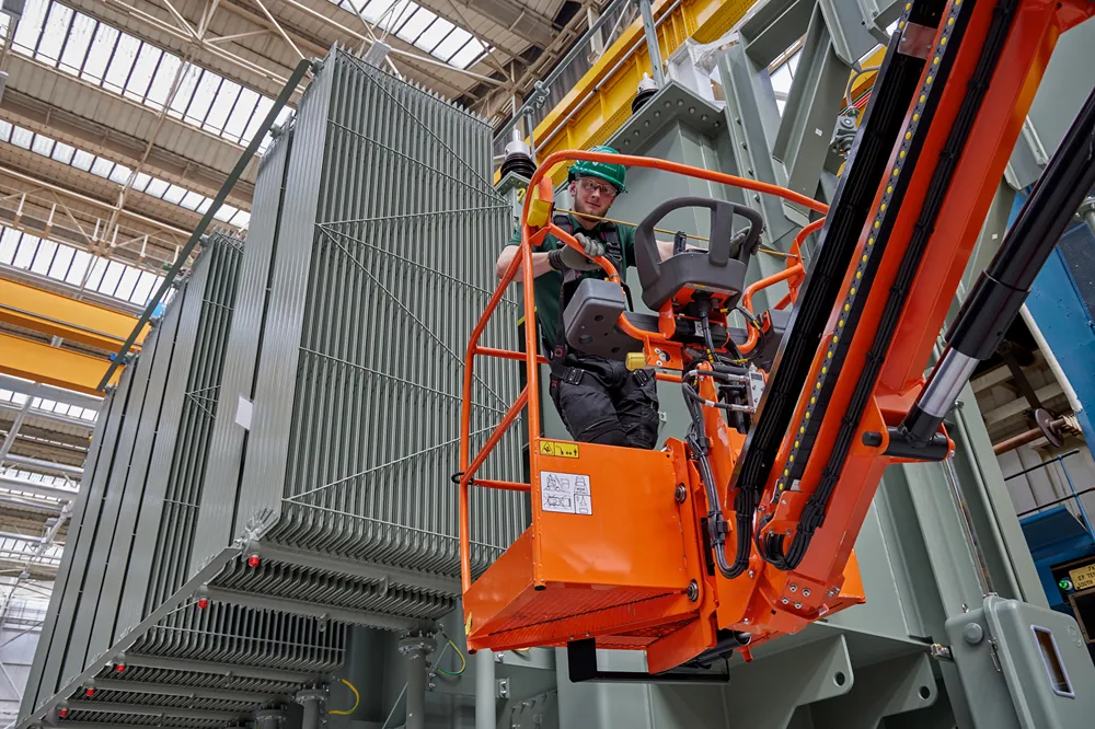 A man wearing safety goggles and hardhat operates a forklift