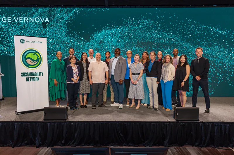 A group of people stand on stage next to a banner that reads Sustainability Network