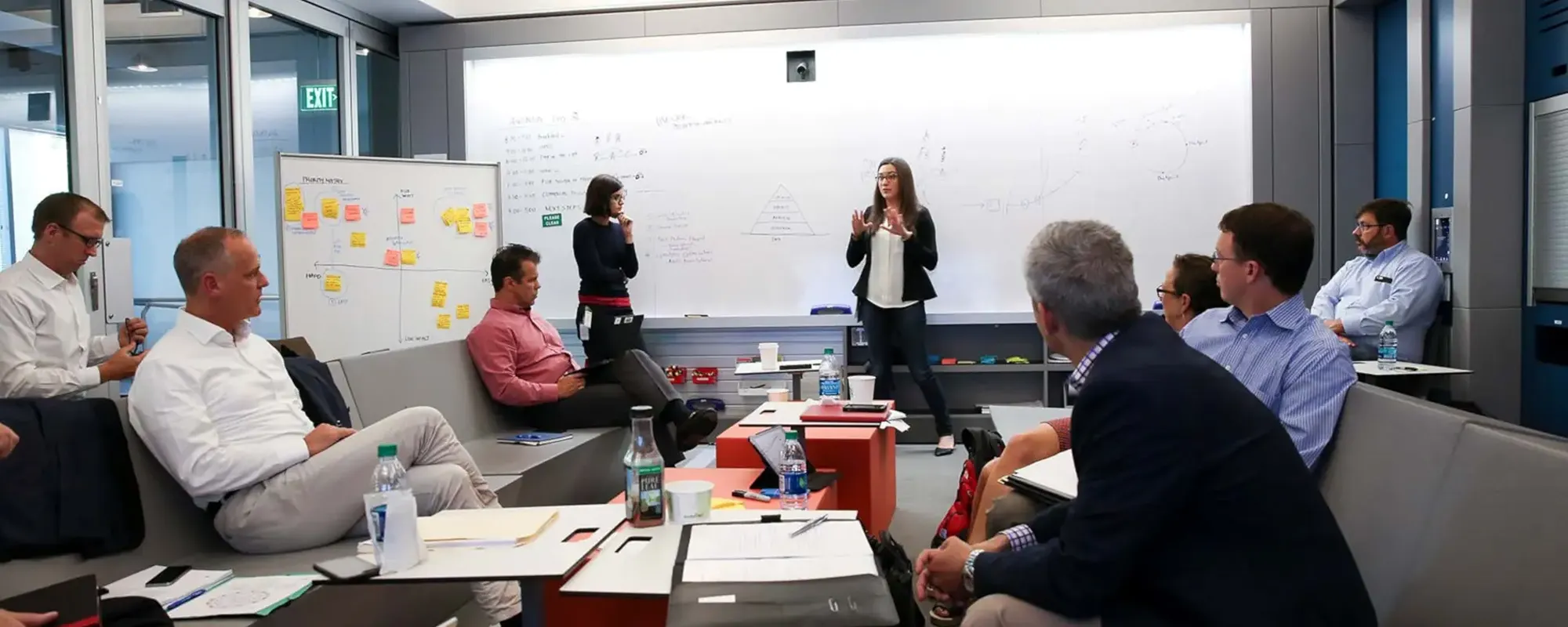 A photo of a group of people inside of a confrence room discussing something