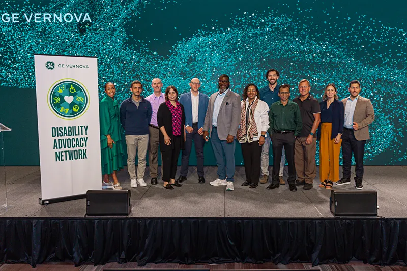 A group of peole stand on stage next to a banner that reads Disabilities Advocacy Network