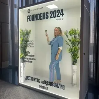 A woman in business attire stands a small silver trophy