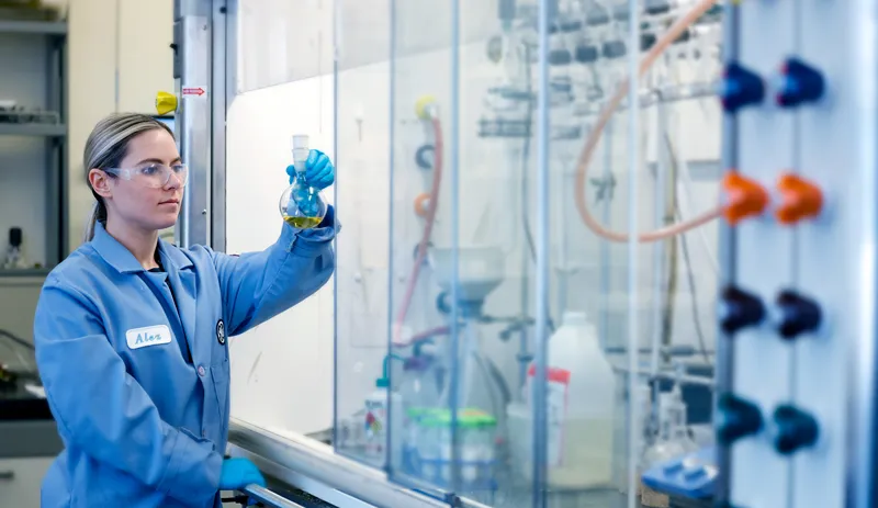 A woman inspecting a yellow liquid inside a glass container