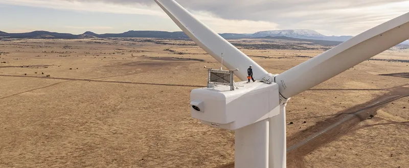 A photo of a person working on top of a wind turbine