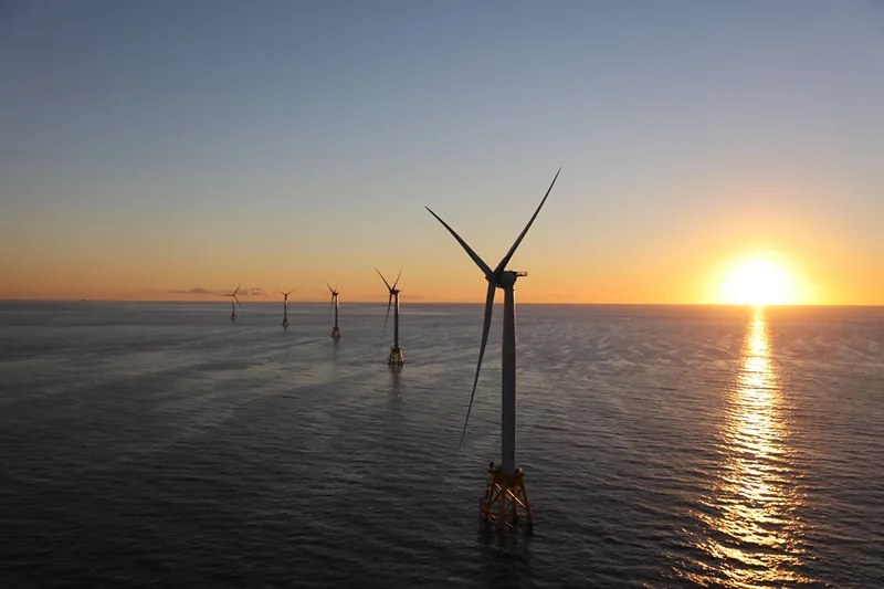 A photo of a group of wind turbines in a large body of water