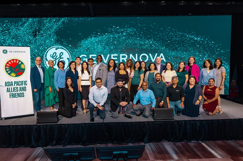 A group of people stand on stage next to a banner that says Asian Pacific Allies and Friends