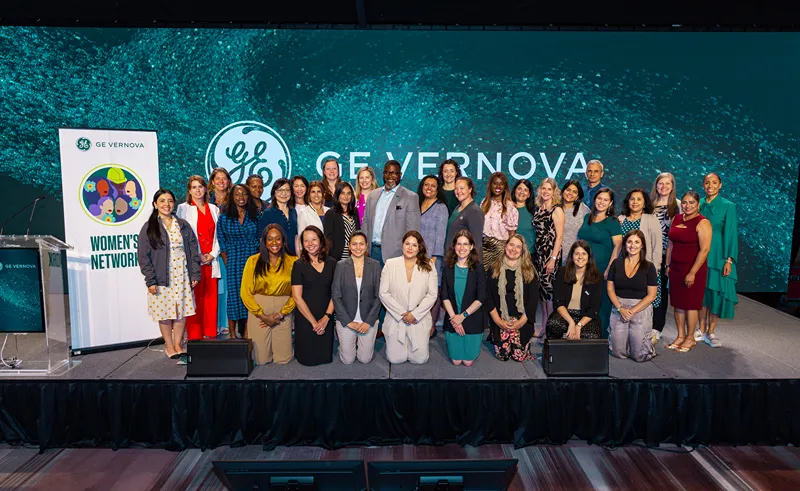 A group of people stand on stage next to a banner that reads Womens Network