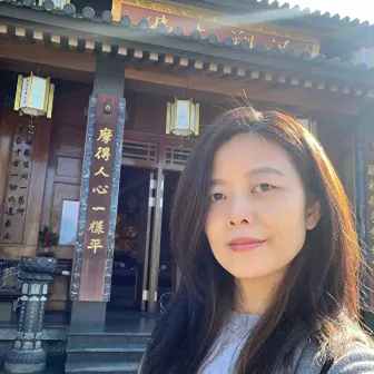 Photo of a woman standing in front of a wooden building