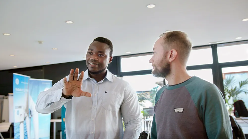 A man in white shirt speaks in front of a group of people
