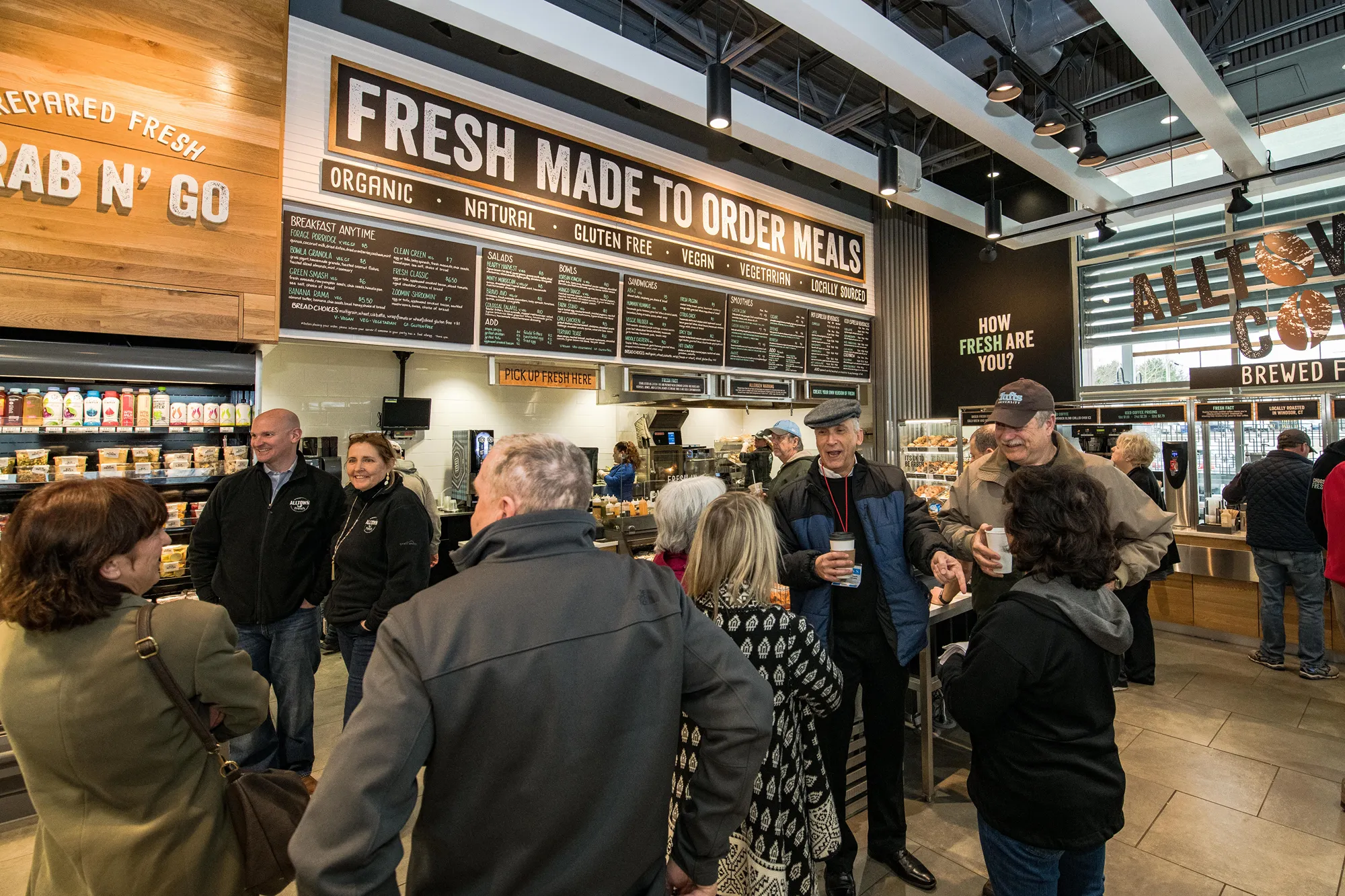 Group of people standing around conversing in a grocery store
