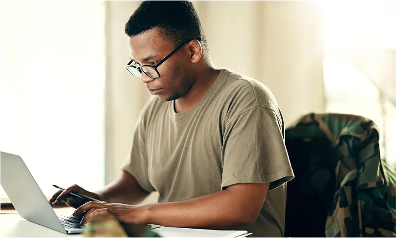 A man wearing glasses working on a laptop computer
