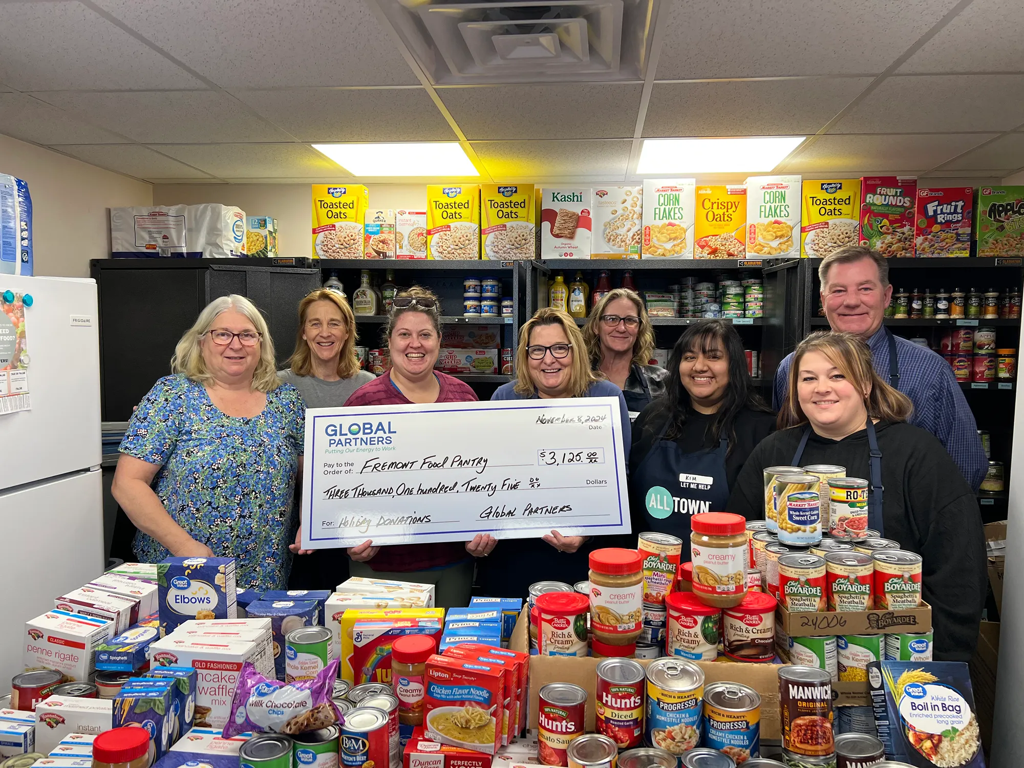 A group of people in a food pantry with stocked shelves