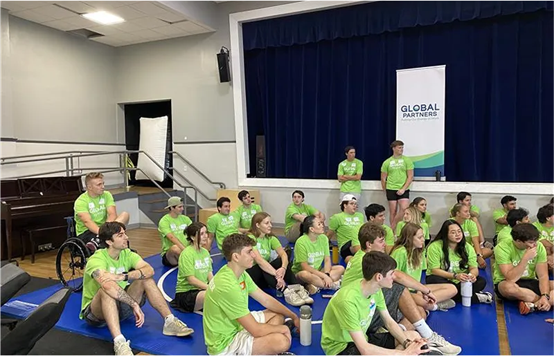 A group of people wearing matching shirts sitting on the floor in a gymnasium