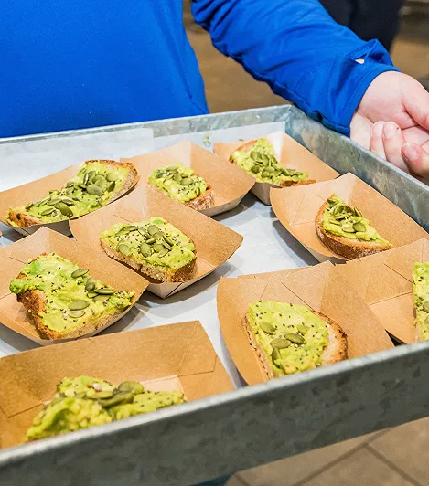A person holding a tray of food samples