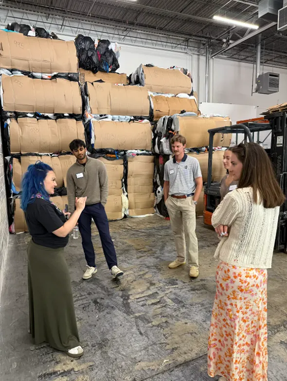 A group of people standing in a circle next to a fork lift