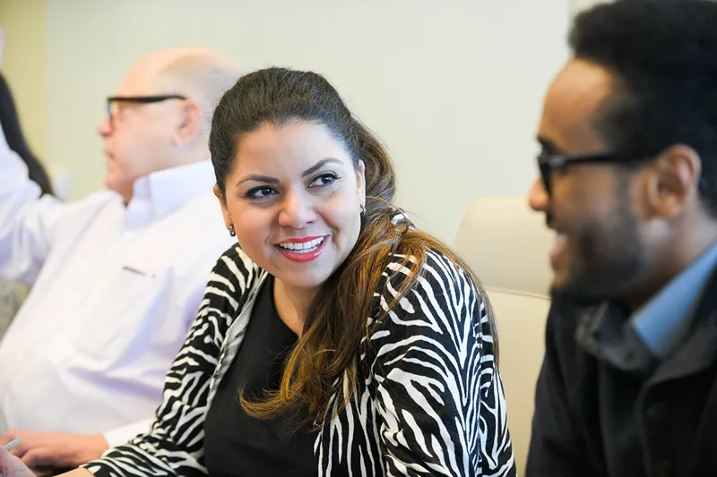 Colleagues smiling and having a friendly conversation during an office meeting.