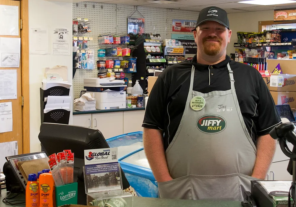 A man standing behind the counter of a convience store