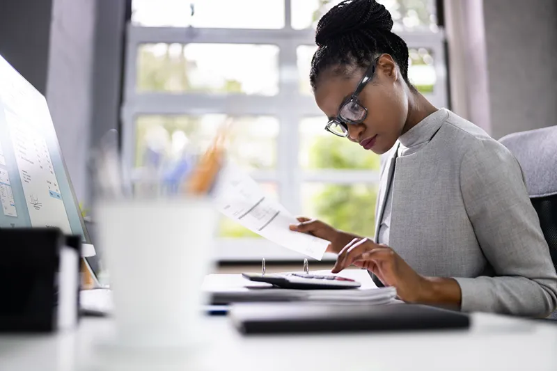 A woman sitting at a desk doing calculations on a calculator