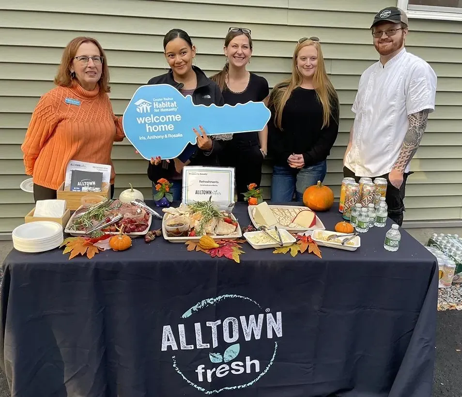 A group of people standing behind a table holding a blue paper key