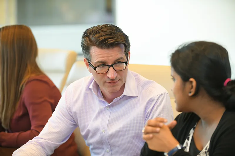 Two colleagues having a focused discussion in a modern office meeting room.