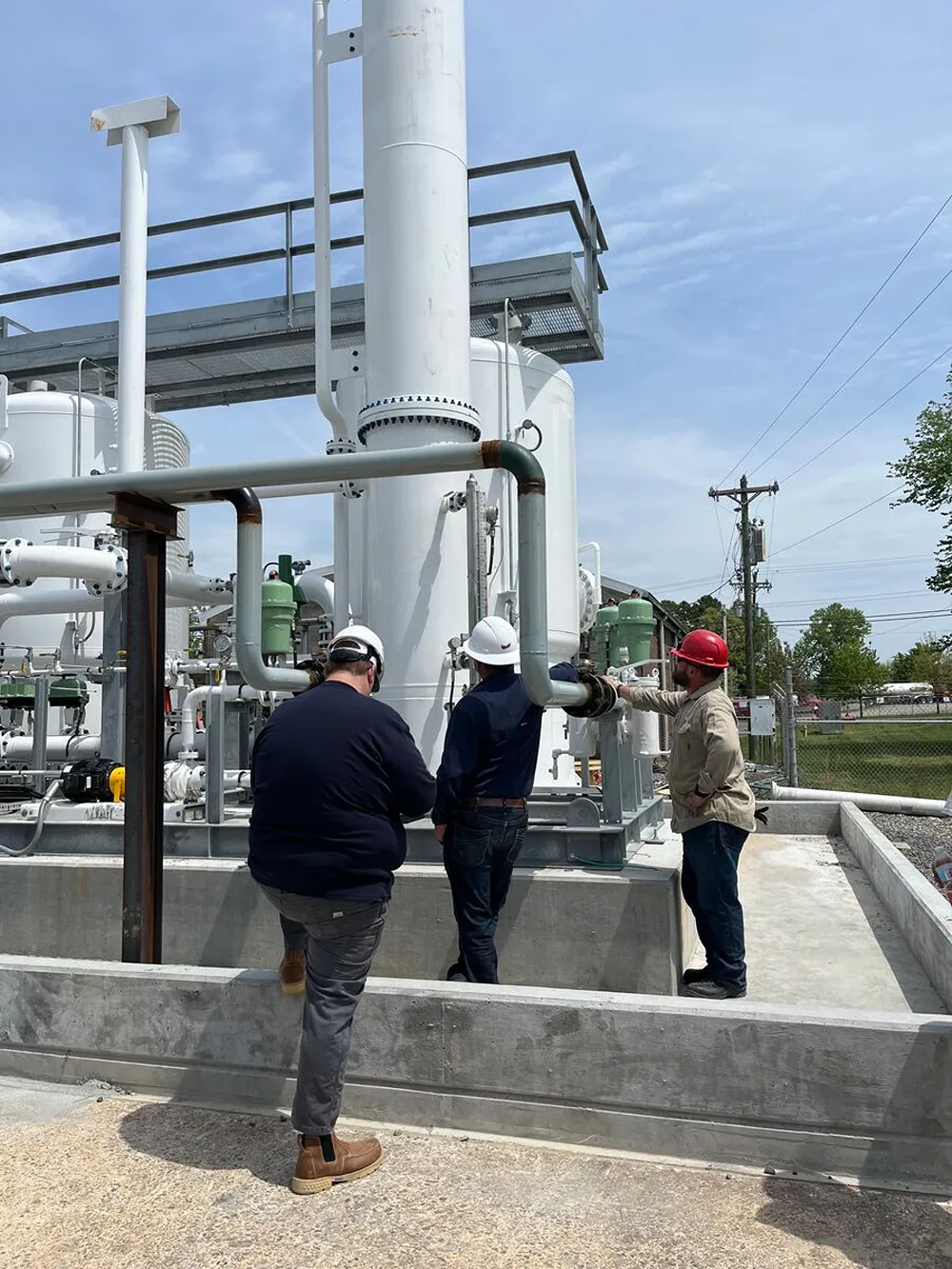 A group of men wearing hard hats working on a complex set of pipes