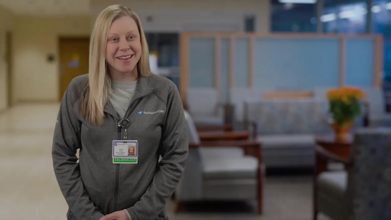 Registered nurse standing in hospital lobby wearing ID badge and white shirt